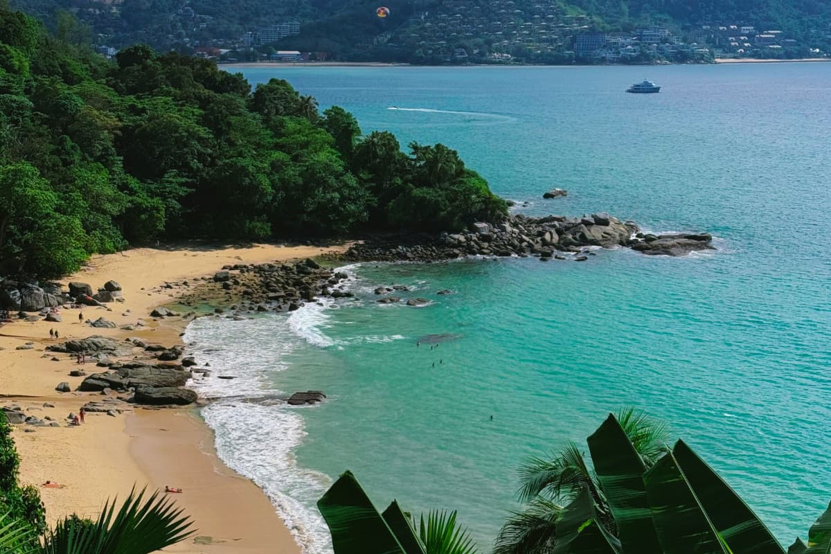 areia da Kata Beach, com vegetação verde nas colinas ao fundo, em Phuket, Tailândia