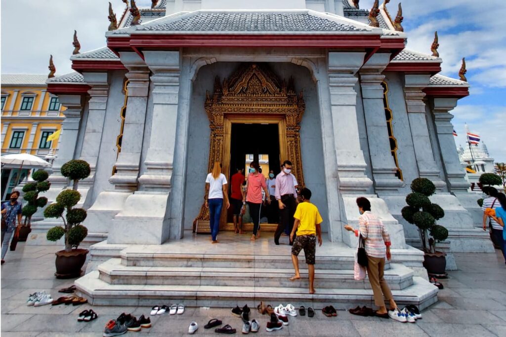 Turistas visitando templo na Tailândia, sapatos deixados na porta do templo.